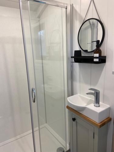 a bathroom with a shower and a sink and a mirror at Peaceful Shepherd’s Hut in beautiful countryside. in Linlithgow