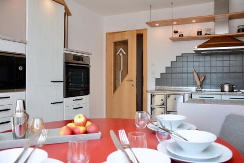 una cocina con una mesa roja con platos y vasos. en Freien Living Angerberg, en Angerberg
