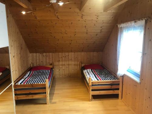 two beds in a wooden room with a window at St Wolfgang-Kienberg - Ruhe und Entspannung mit bester Aussicht in Obdach