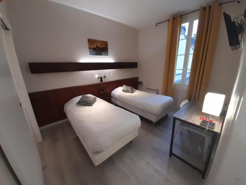 a small room with two beds and a table at Contact Hotel de France in Saintes