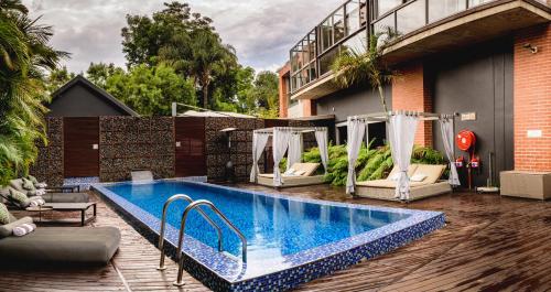 a swimming pool with two swing chairs and a building at Menlyn Boutique Hotel in Pretoria