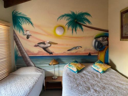 a bedroom with two beds with a palm tree mural at Aruba , Eagle Beach Townhouse in Palm-Eagle Beach