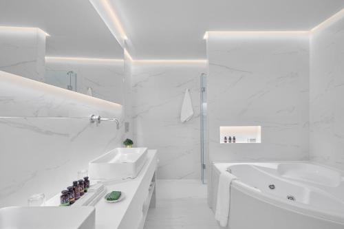 a white bathroom with two sinks and a tub at Grand Hotel Palace in Thessaloniki