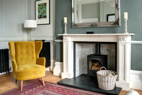 a living room with a fireplace with a chair and a mirror at 16 Lansdown Flat 3 - By Luxury Apartments in Cheltenham