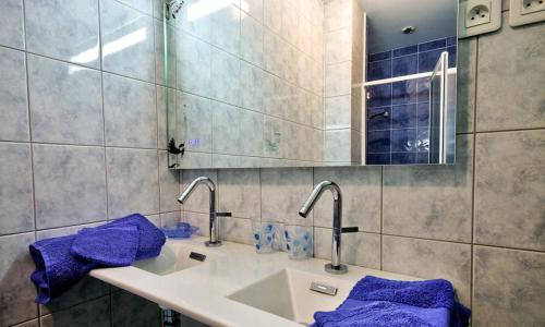ein Badezimmer mit einem Waschbecken, einem Spiegel und lila Handtüchern in der Unterkunft Ty an Aod in Kerlaz