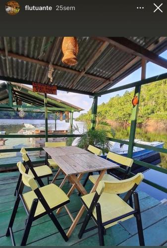 a wooden table and chairs on a deck at Pousada Amazônia Encantada in Iranduba