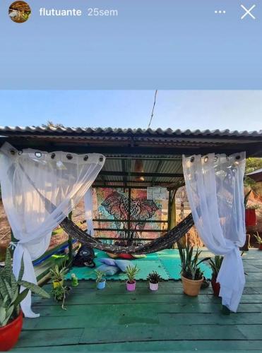 a porch with white curtains and potted plants at Pousada Amazônia Encantada in Iranduba