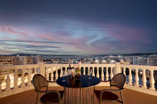 a table on a balcony with a view of a city at Grand Hotel Palace in Thessaloniki