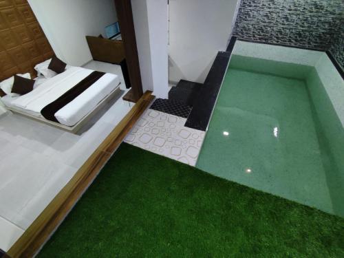 a room with a swimming pool and a bed and grass at Hotel Jurkis, Kolhapur in Kolhapur
