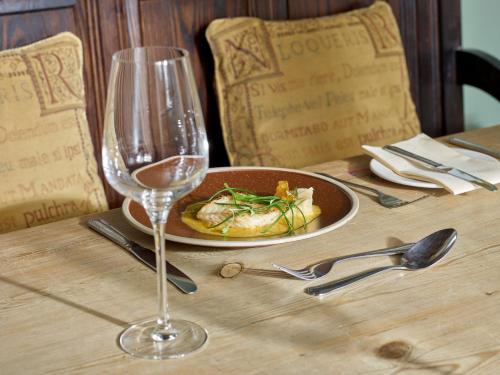 a table with a plate of food and a wine glass at The Plough Inn in Stalisfield