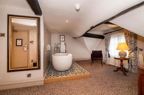 a bathroom with a tub and a chair and a mirror at Greswolde Arms by Chef & Brewer Collection in Solihull