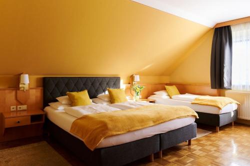 2 łóżka w pokoju z żółtymi ścianami w obiekcie Hotel Garni Thermenoase w mieście Bad Blumau