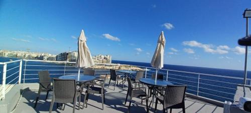 a balcony with tables and chairs and the ocean at Valletta Dream Suites in Valletta