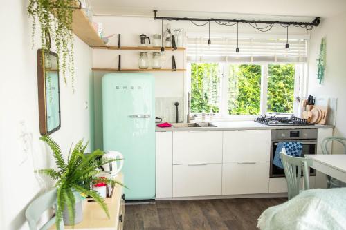 een keuken met witte kasten en een blauwe koelkast bij Strand-chalet Luna - 700 mtr van het strand van Ouddorp in Ouddorp