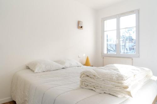 ein weißes Bett in einem weißen Zimmer mit Fenster in der Unterkunft Maison de bourg a deux pas de la mer in Saint-Brevin-les-Pins