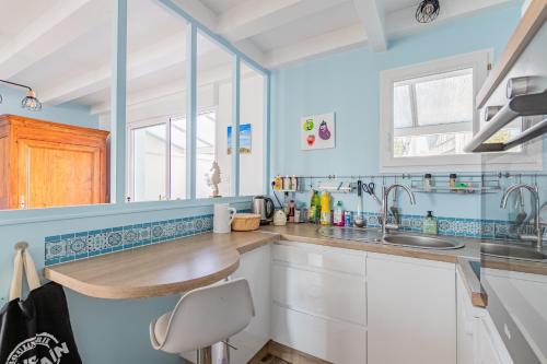 una cocina azul con armarios blancos y fregadero en Villa moderne et coloree a Jard sur mer, en Jard-sur-Mer
