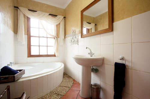 a bathroom with a tub and a sink and a mirror at Finchley Farm Cottages in Willowmore