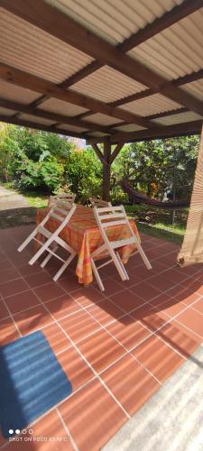 eine Terrasse mit einem Tisch und einer Bank unter einem Dach in der Unterkunft Studio en rez de jardin in La Trinité