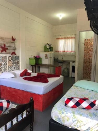 een slaapkamer met 2 bedden en een keuken met een koelkast bij Recanto dos Pássaros in Peruíbe