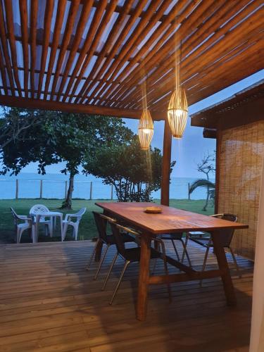 un tavolo e sedie in legno su una terrazza con luci di Casa Beira Mar Pitinga a Arraial d'Ajuda