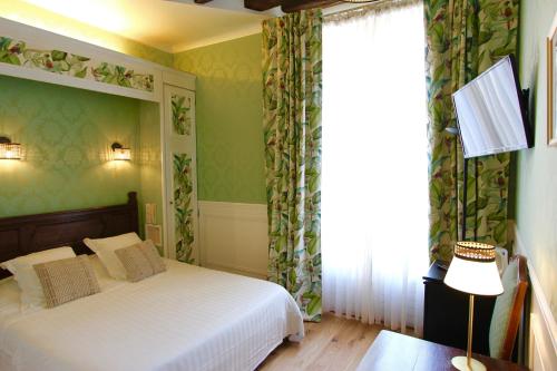 a bedroom with a bed with green walls and a window at Hotel de la Bretonnerie in Paris