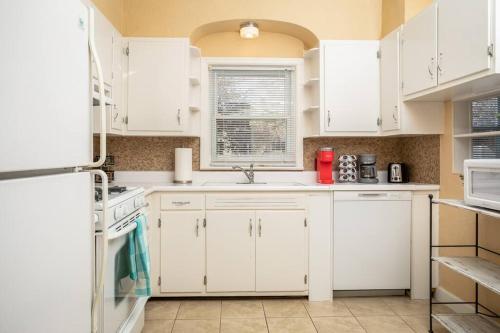 a white kitchen with white cabinets and a window at Shenandoah Getaway Near National Park Cozy Space! in Shenandoah