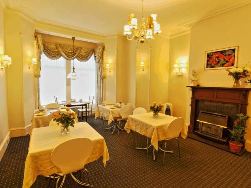 een kamer met tafels en stoelen en een open haard bij Brentwood Villa Bed and Breakfast in Aberdeen
