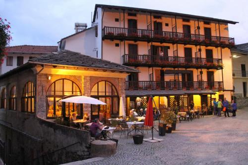 een groep mensen die aan tafels voor een gebouw zitten bij Albergo Miniere in Traversella