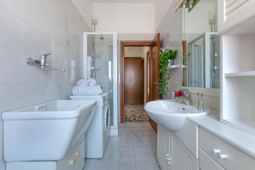 - une salle de bains blanche avec deux lavabos et un miroir dans l'établissement a 500 mt dalla Certosa Apartment, à Bologne