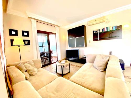 ein Wohnzimmer mit einem weißen Sofa und einem TV in der Unterkunft Villa Ágatha, vacaciones en familia en Lanzarote in Playa Blanca