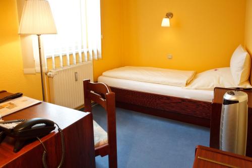 a room with a bed and a desk with a telephone at Landhotel Zum Pottkuchen in Kalbe