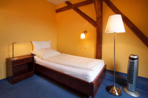 Dormitorio pequeño con cama y lámpara en Landhotel Zum Pottkuchen, en Kalbe