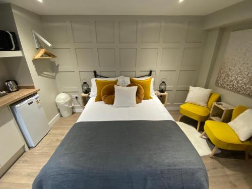 1 dormitorio con 1 cama grande y 2 sillas amarillas en Greenbank, Lower Greenbank Guest Suite, en Oban