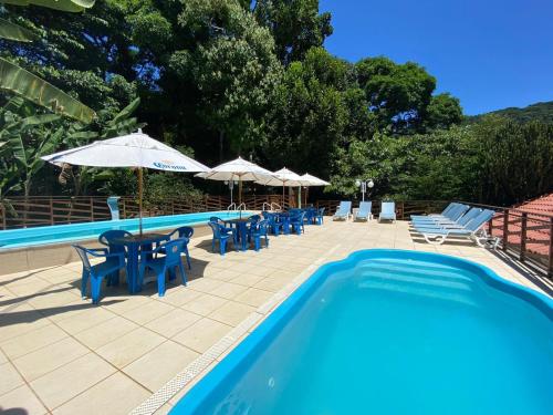 a swimming pool with chairs and tables and umbrellas at Pousada Mata Nativa in Abraão