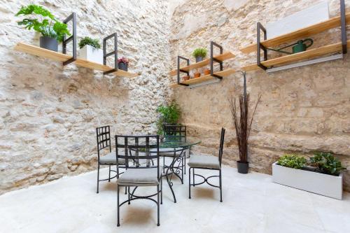 une table et des chaises dans une pièce avec un mur en pierre dans l'établissement Jardin Secret Studio Terrasse Panier Vieux-Port Marseille, à Marseille