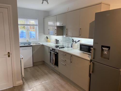 uma cozinha com armários brancos e um frigorífico de aço inoxidável em The Sorting House em Hunstanton