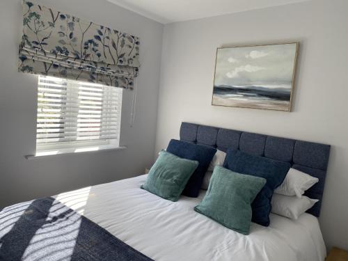 Schlafzimmer mit einem Bett mit blauen und weißen Kissen in der Unterkunft The Sorting House in Hunstanton