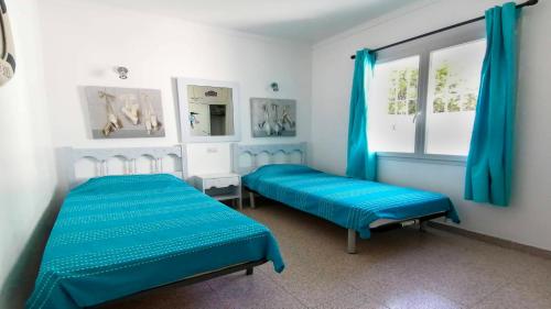 レスカラにあるVACAY Villa Bellaの青いカーテンが備わる客室のベッド2台