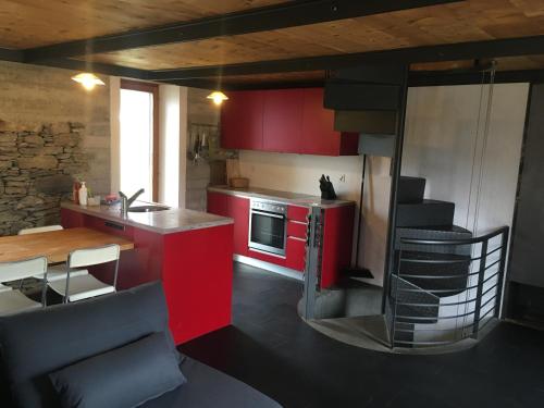 a kitchen with red cabinets and a table and a kitchen with a stove at RUSTICO CONCEPRIO & SAUNA in Corzoneso