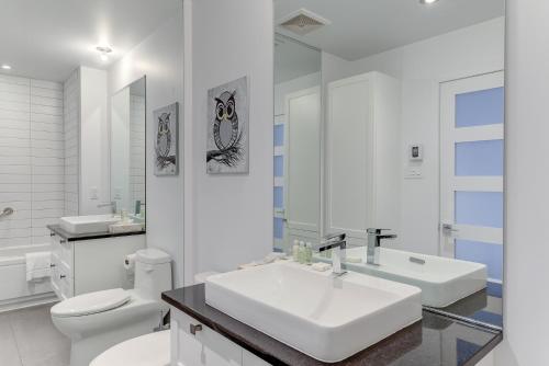 Baño blanco con lavabo y aseo en Les Immeubles Charlevoix - Le 760310 en Quebec