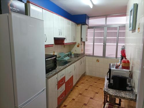 a kitchen with white cabinets and a sink and a refrigerator at Apartamentos San Antón 2 in Córdoba