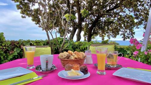Una mesa rosa con una cesta de pan y vasos de zumo de naranja. en La Tour, en Linguizzetta