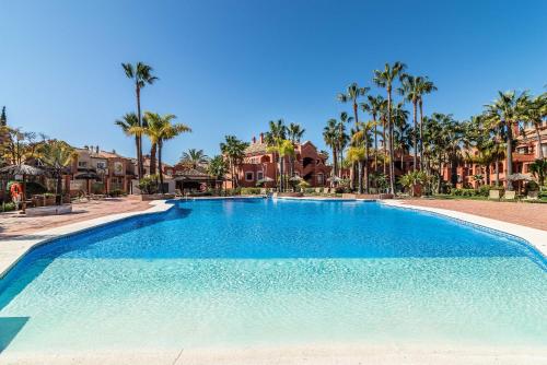 una gran piscina con palmeras y casas en Solvasari, en Marbella
