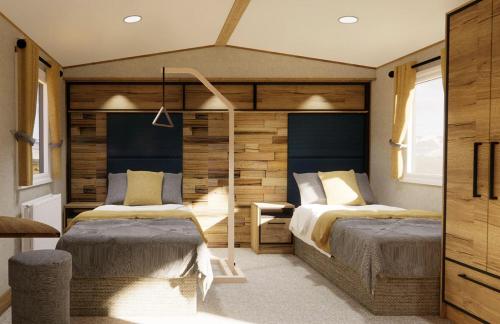 a bedroom with two beds and a wooden wall at Mill Rythe Coastal Village in South Hayling