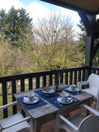 een houten tafel op een balkon met borden en kopjes bij le Pullman in Deauville