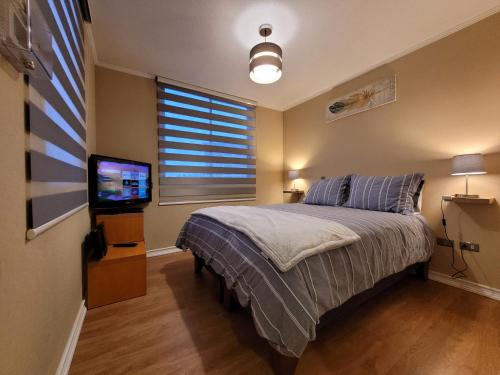 a bedroom with a bed with a television and a window at San Pedro de la Paz by Luxury Apartment Chile in San Pedro de la Paz