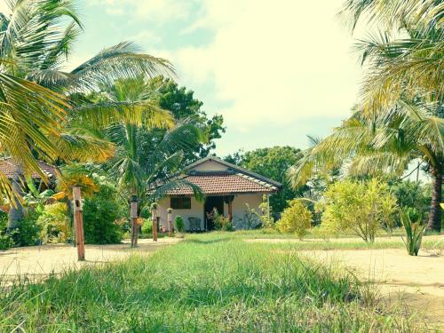a house with palm trees in front of it at Prime Surfers Bungalow in Arugam Bay