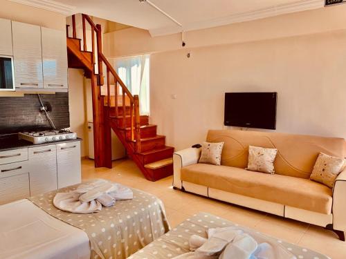 a living room with a couch and a staircase at ERİKLİ SUNSHİNE HOLİDAY APART HOTEl in Erikli