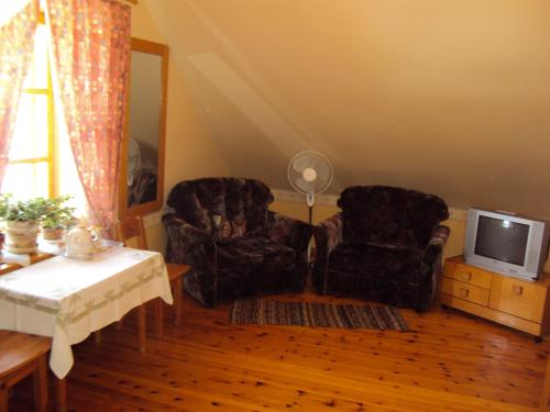 a living room with two chairs and a tv at Saule in Talsi