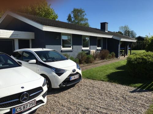 two white cars parked in front of a house at Hasmark beach, nice house close to the beach. in Otterup